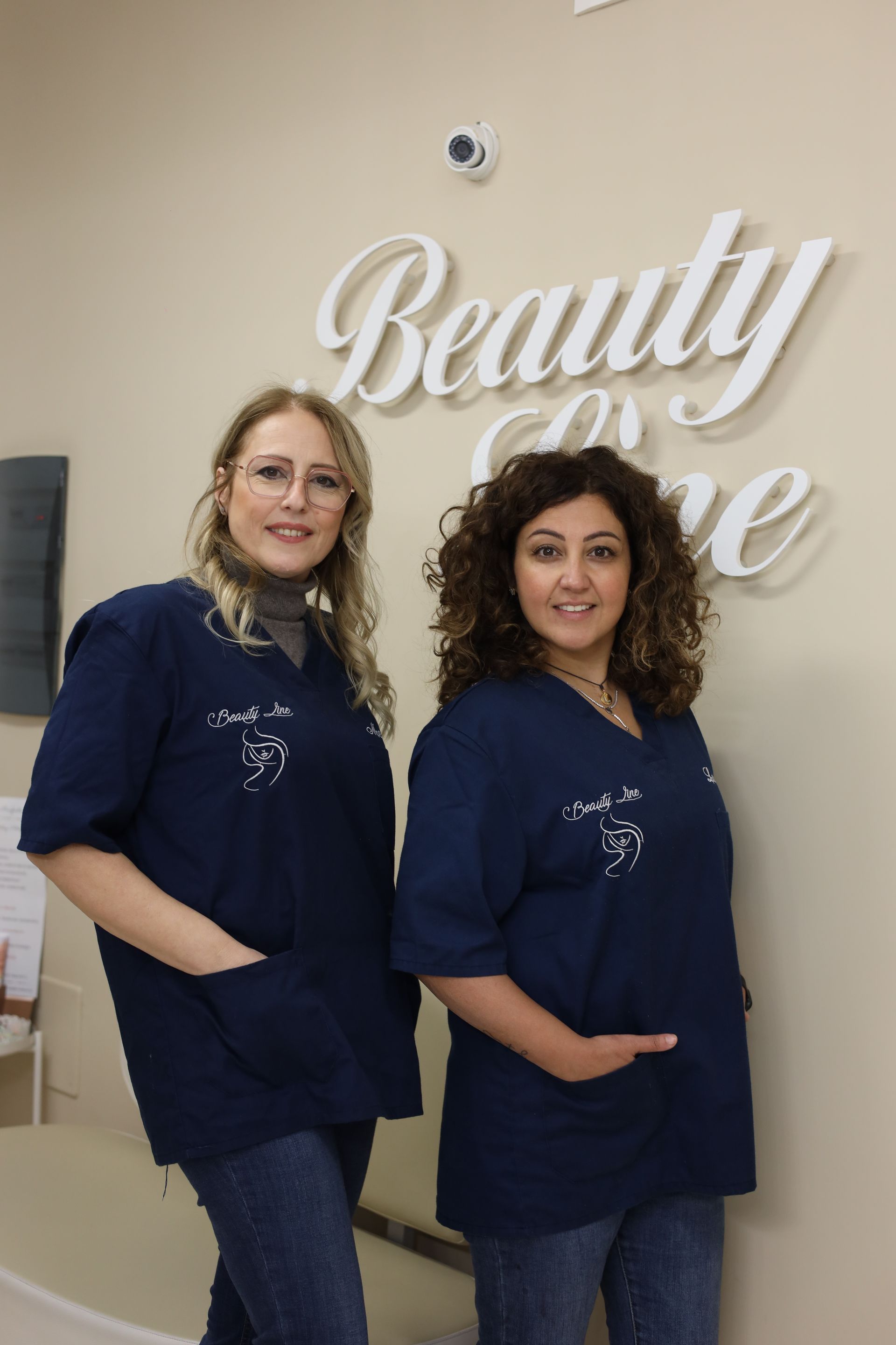 Due persone che indossano camici blu sono in piedi vicino a un cartello con la scritta 