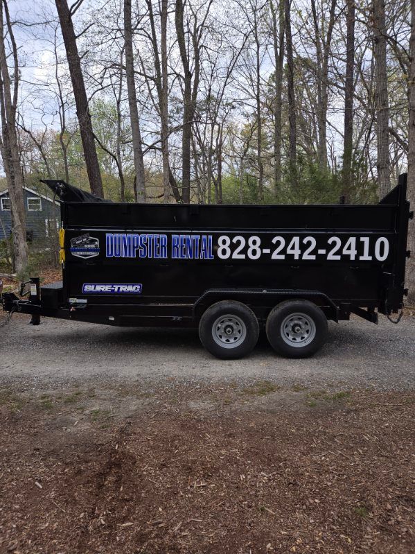 A large blue dumpster is parked in front of a house under construction.