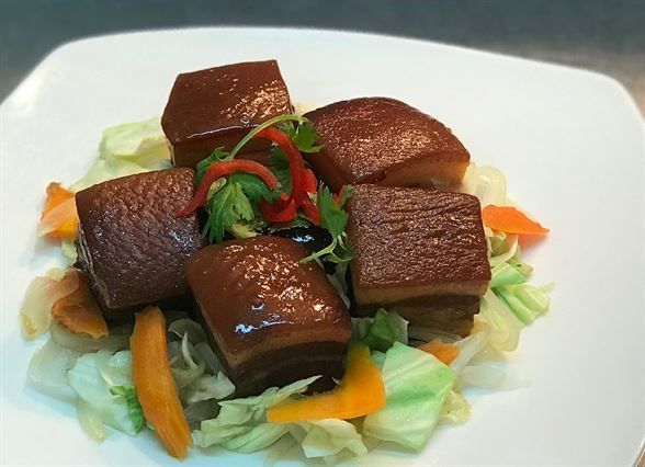 A white plate topped with meat and vegetables on a table.