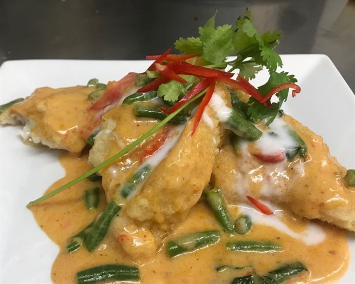 A plate of food with sauce and green beans on it