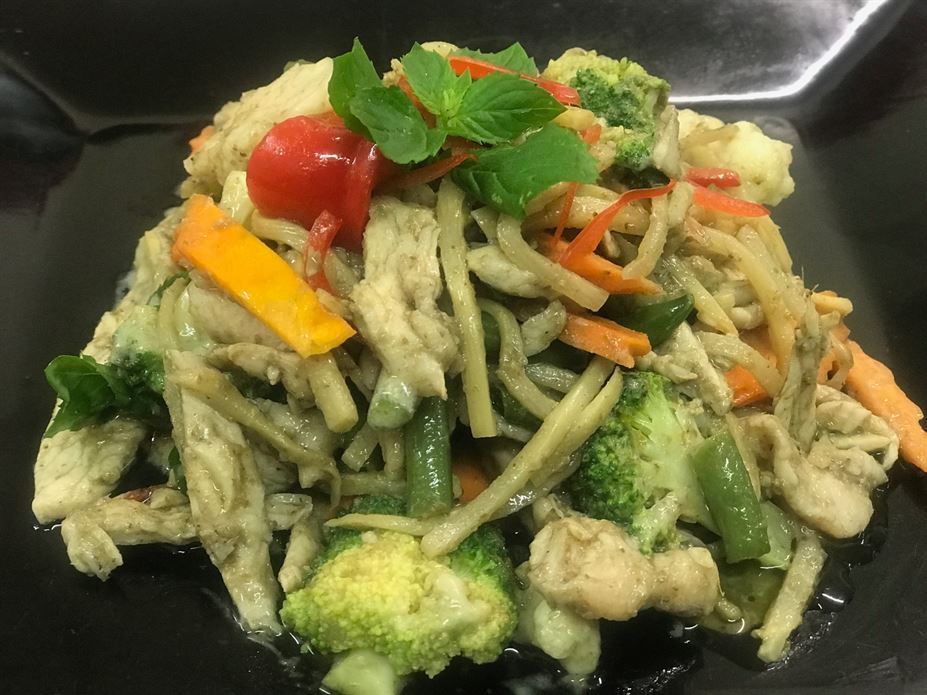 A close up of a plate of food with noodles and vegetables on a table.
