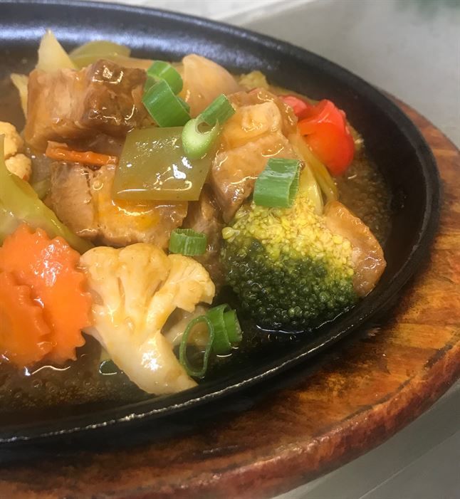 A close up of a plate of food on a wooden table.