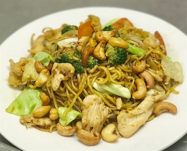 A white plate topped with noodles , chicken , broccoli and cashews.