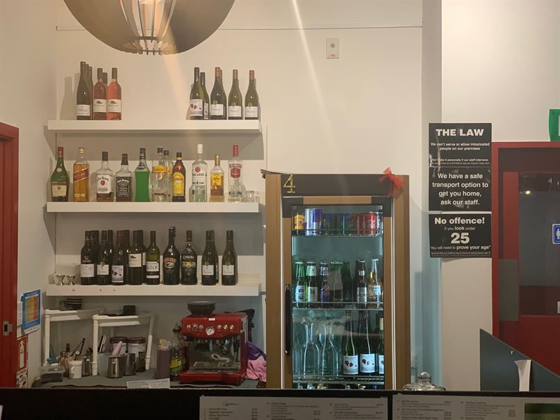 A bar with bottles of alcohol on shelves and a refrigerator.