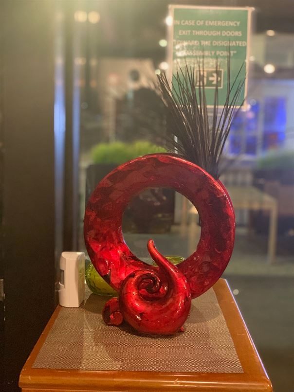 A red sculpture is sitting on a wooden table