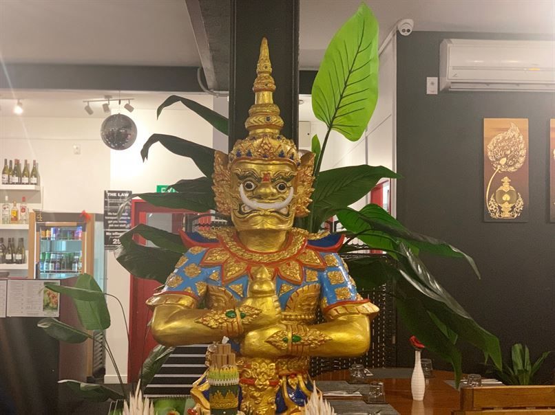 A statue of a giant standing next to a plant in a restaurant.
