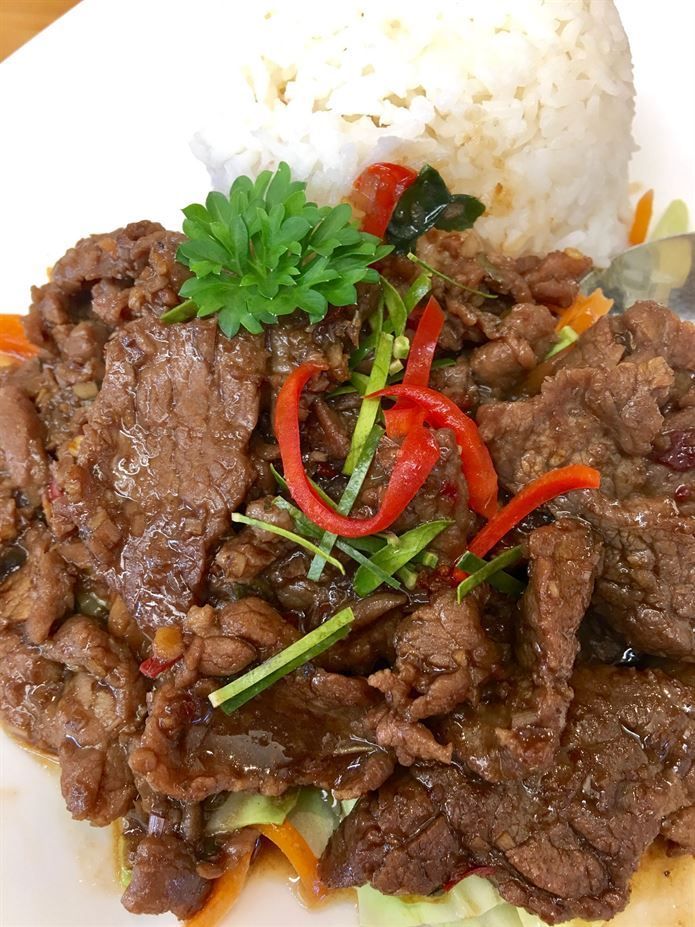 A close up of a plate of food with meat and rice on a table.