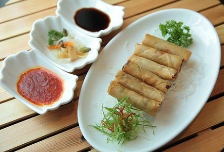 A plate of food with dipping sauces on a wooden table.