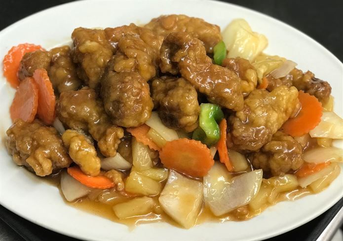 A white plate topped with meat and vegetables on a table.