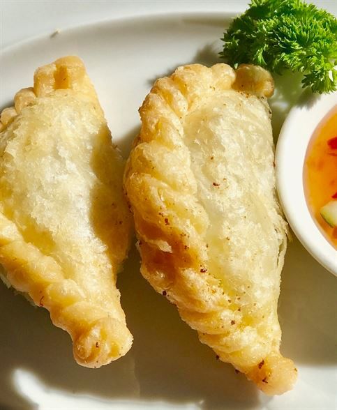 A white plate topped with fried food and a bowl of dipping sauce
