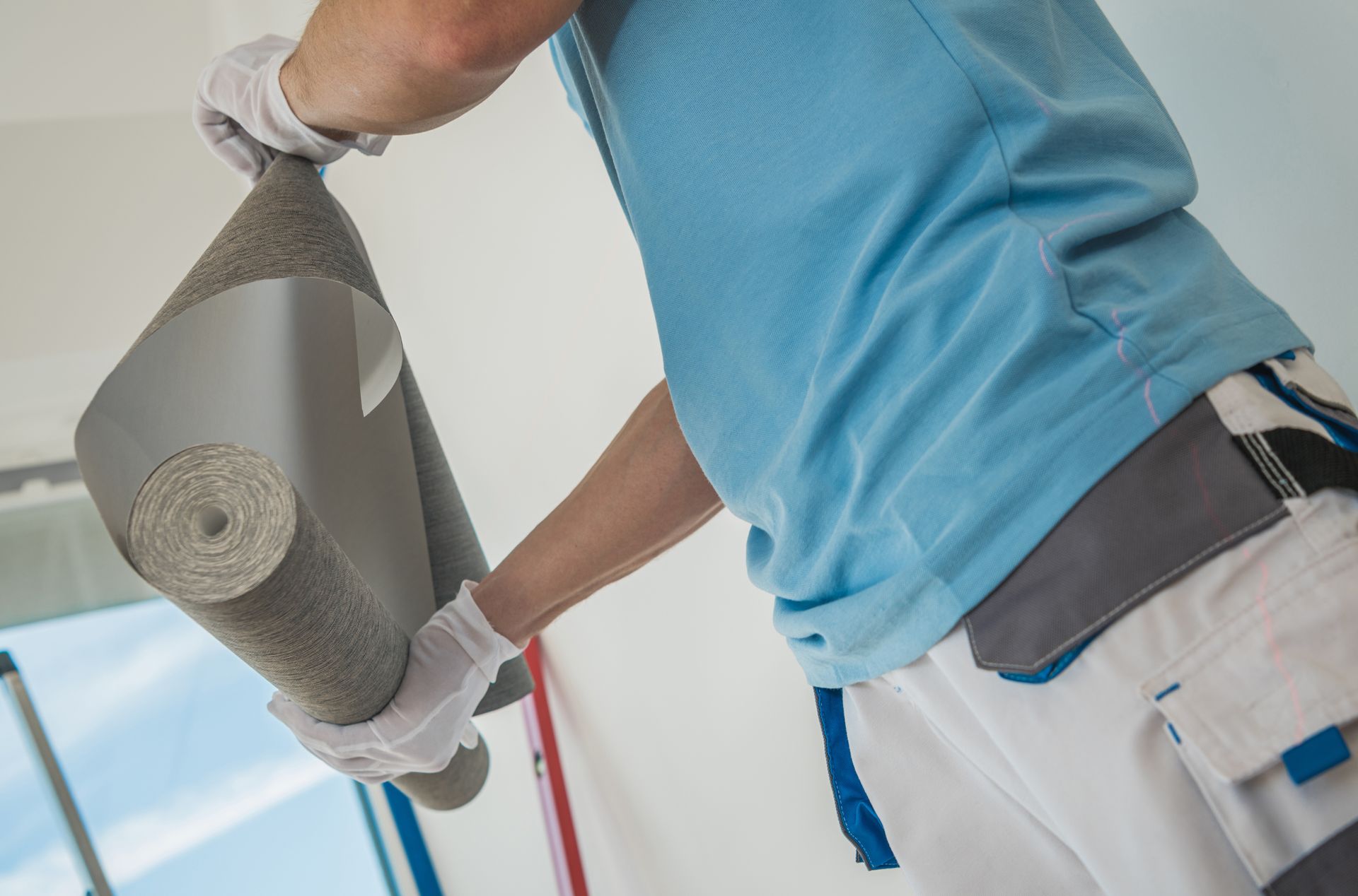 Man Preparing Roll of Modern Vinyl Wallpaper For an Installation.