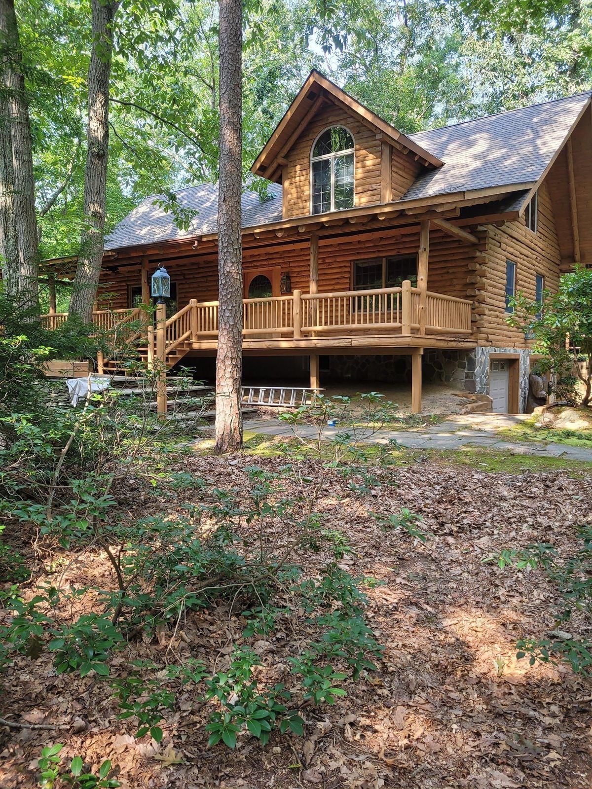 A large log cabin in the middle of a forest surrounded by trees.