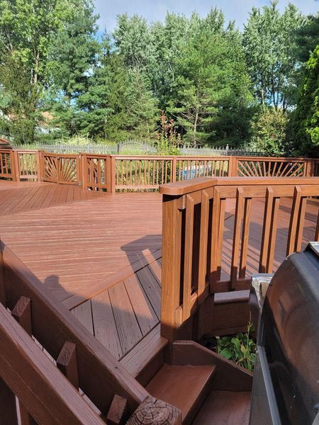 A wooden deck with stairs leading up to it and trees in the background.