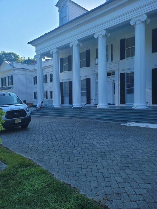 A white van is parked in front of a large white building.