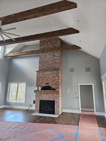 A living room with a brick fireplace and wooden beams.
