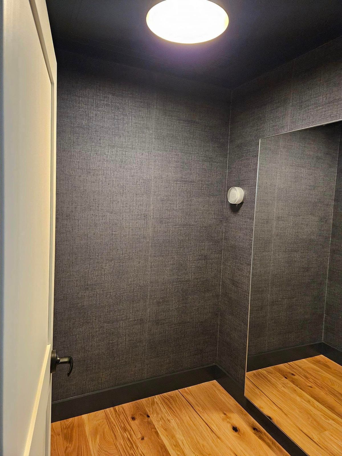 A room with a mirror and a light on the ceiling.