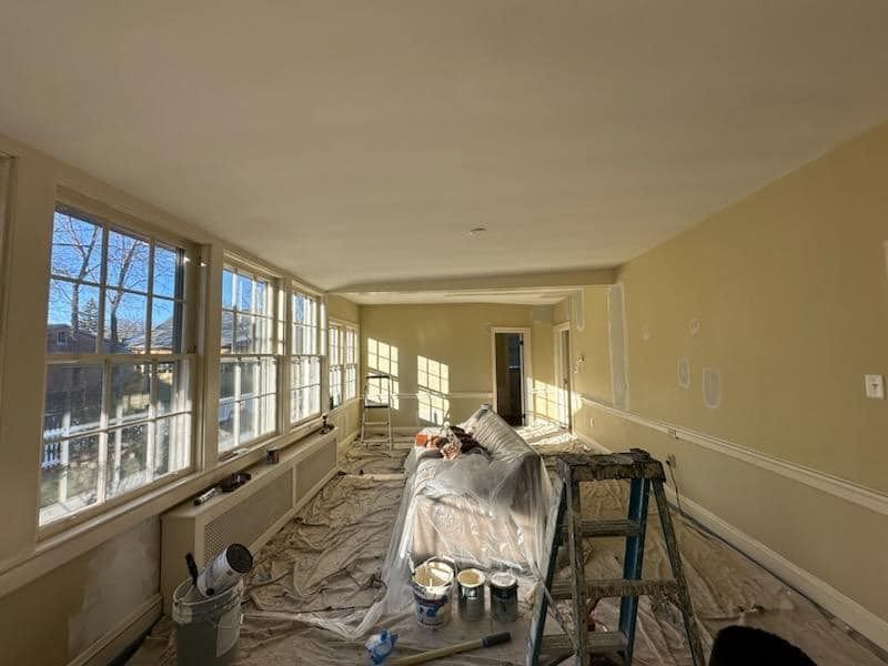 A large room with a lot of windows is being painted.