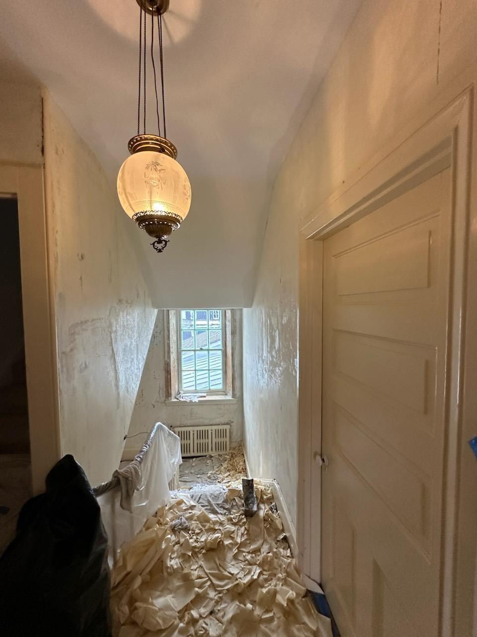 A hallway with a light hanging from the ceiling and a window.