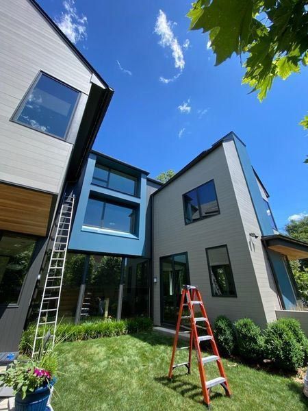 A ladder is sitting in front of a large house with newly painted white walls.