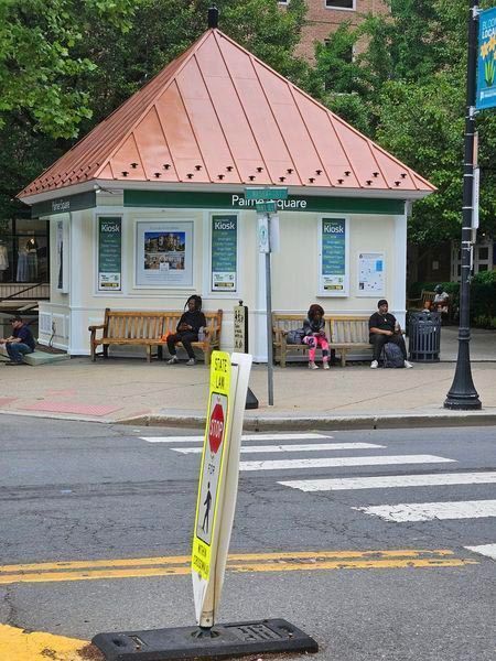People sit on benches in front of a park and ride