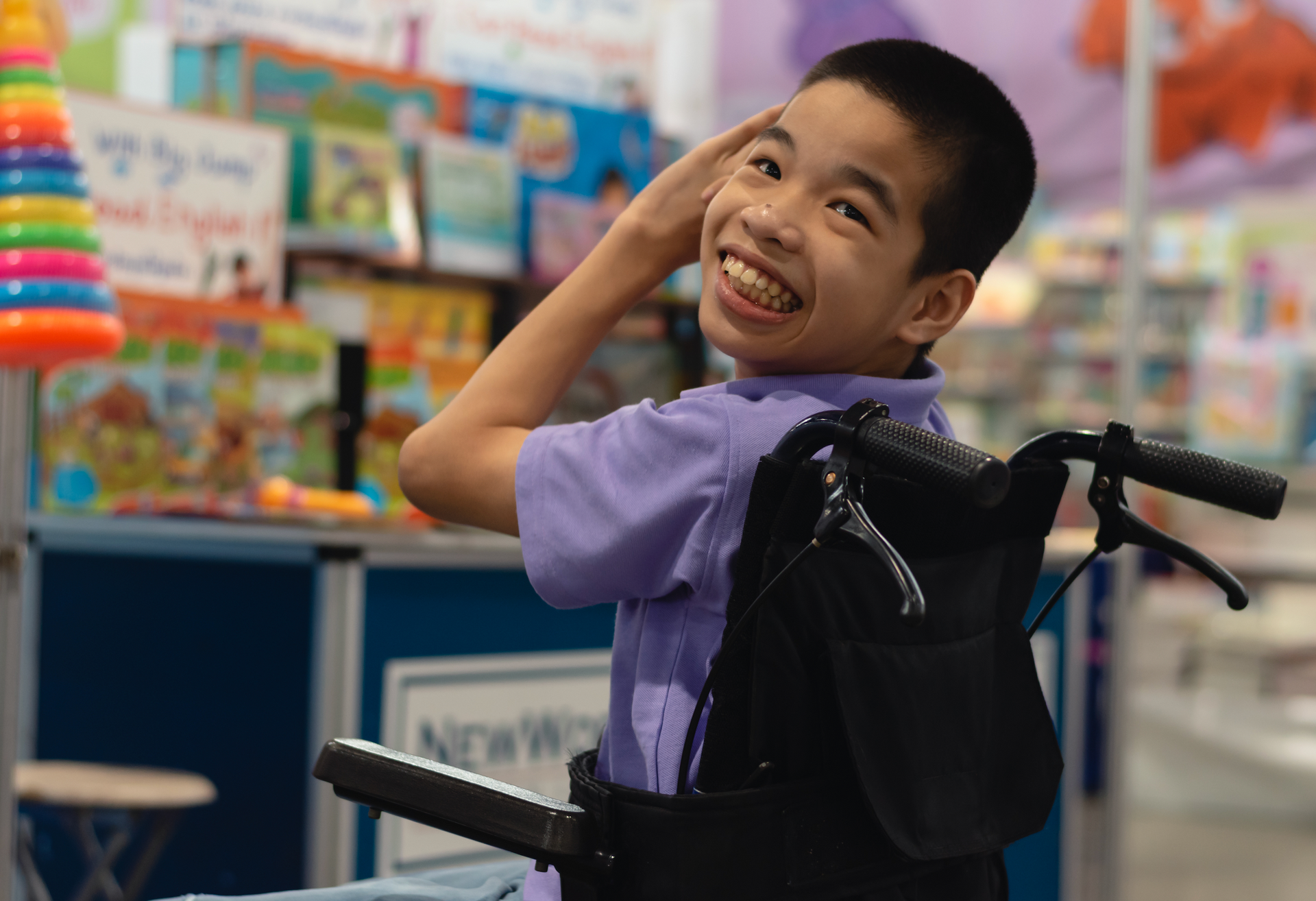 A young boy in a wheelchair is smiling in a store.