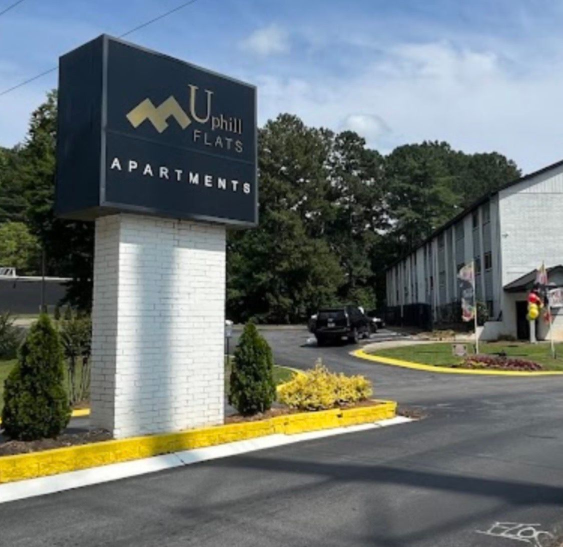 Apartment entrance sign at Upton Farms with landscaped driveway and buildings in the background
