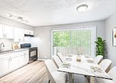 Bright modern kitchen and dining area with white cabinets, large window, and round table set for a meal