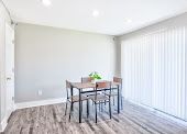 Bright dining area with a small table, four chairs, gray walls, and vertical blinds by a sliding door