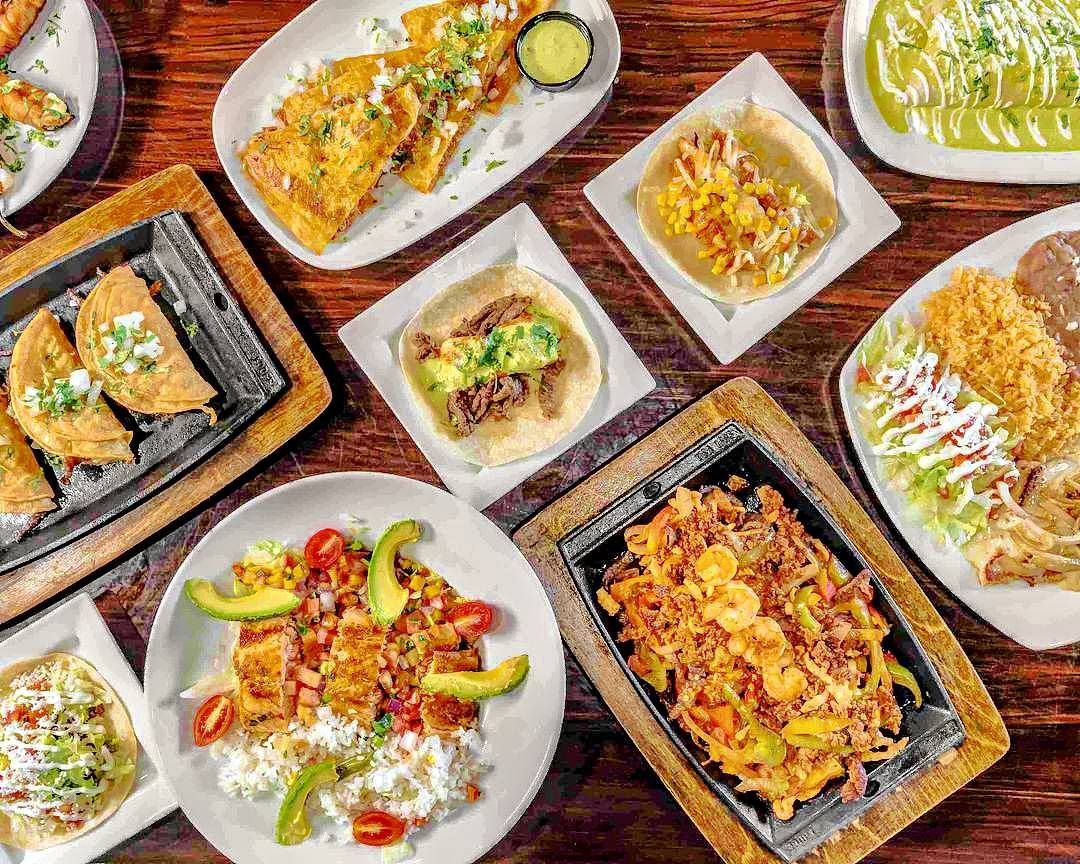 Photo of various plates of Mexican food on a brown table