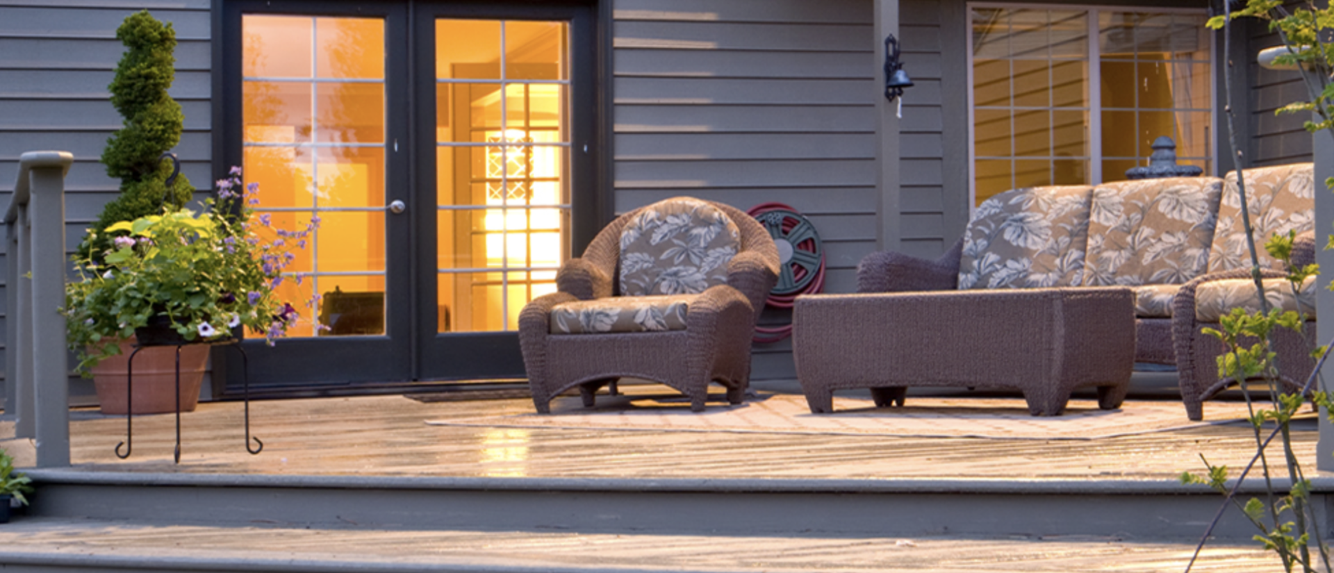 A patio with a couch , chairs , and a table in front of a house.