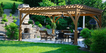 A wooden pergola is sitting in the middle of a lush green yard.