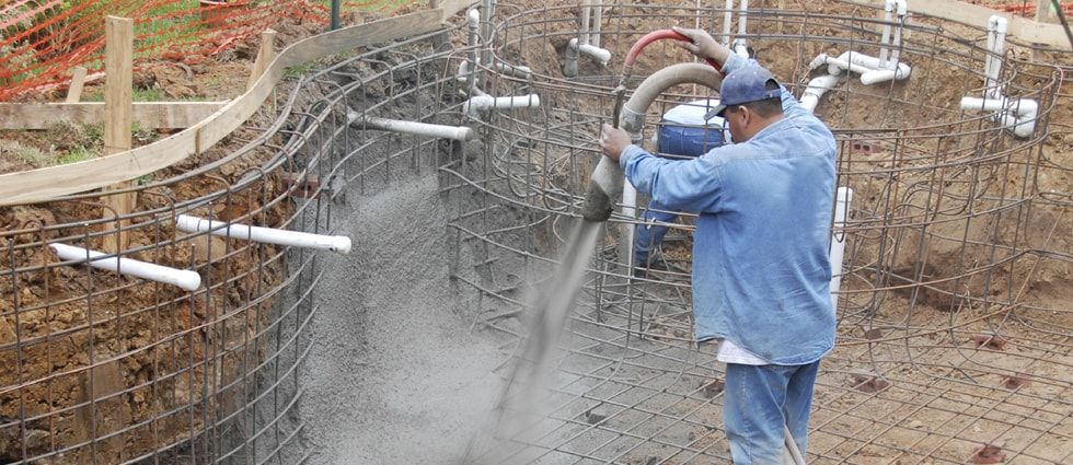 A man is pouring concrete into a pool.