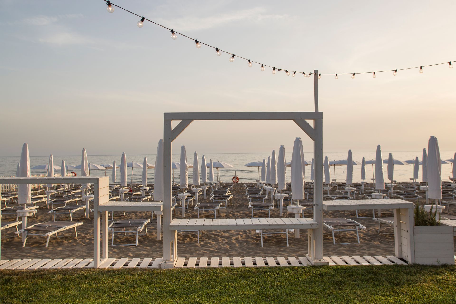 C'è una panchina sulla spiaggia con degli ombrelloni sullo sfondo.