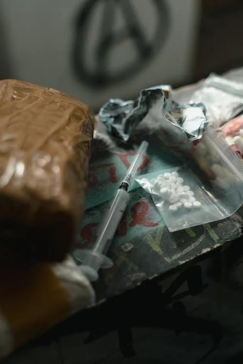 Scattered pills, syringes, and scissors on a table symbolizing substance dependence and the need to 