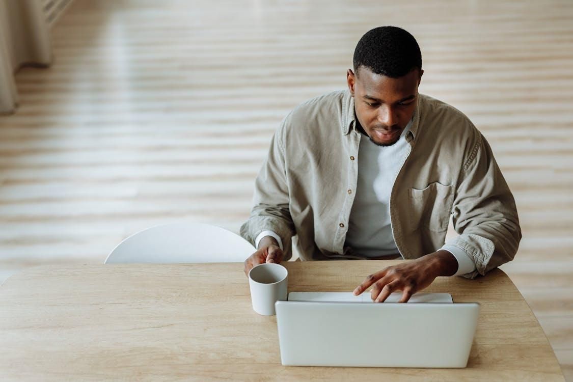 a man sitting with his laptop and a cup for a mobile therapy session