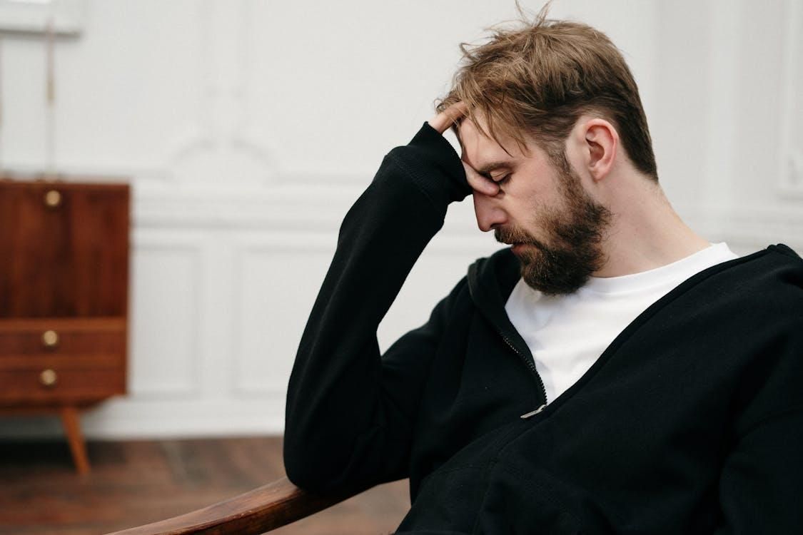A person in a black blazer holding their head