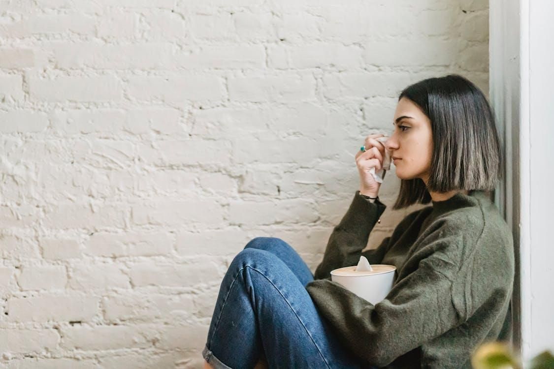 Woman sitting with her knees pulled up, visibly distressed and struggling with mental health issues