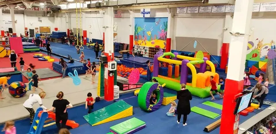 a group of children are playing in a gym with a bouncy house