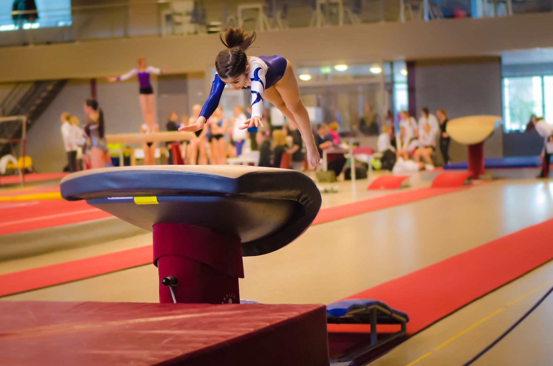 a female gymnast is doing a trick on a balance beam in a gym