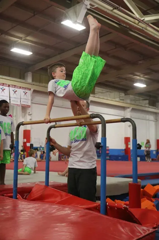 a young boy is doing a handstand on a parallel bars in a gym