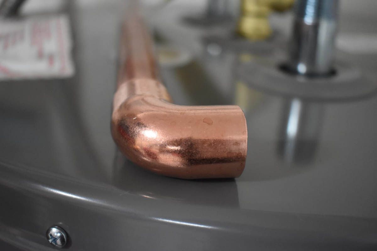 Copper pipe elbow resting on top of a water heater.
