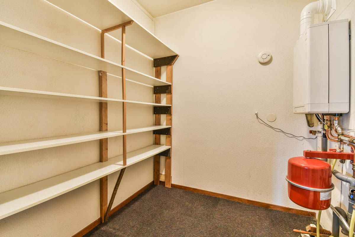 Shelves in storage room next to a wall with heating equipment.