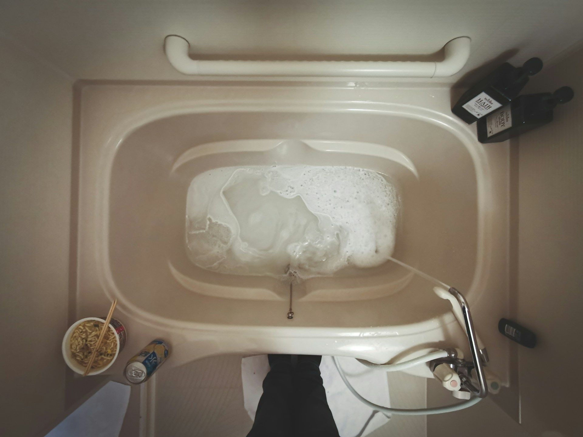 Overhead view of a bathtub filled with bubbly water, toiletries nearby.