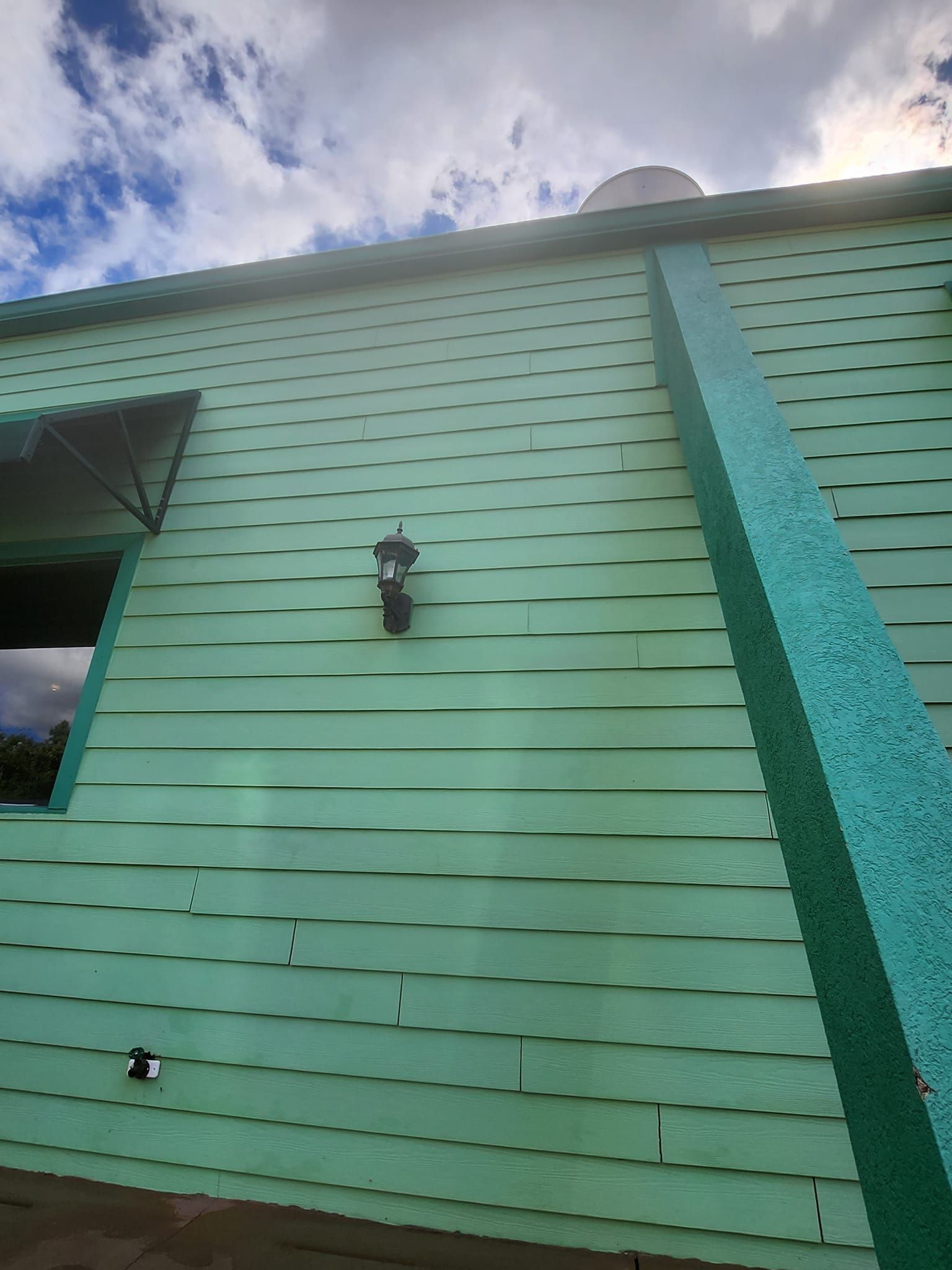 A green building with a light on the side of it