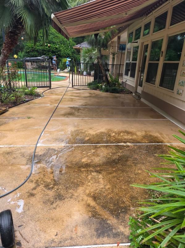 A white house with a garage and a driveway in front of it surrounded by trees.