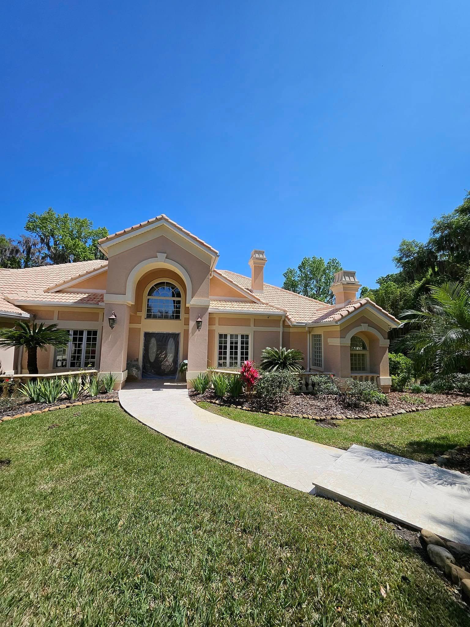 A large house with a lush green lawn and a walkway leading to it.