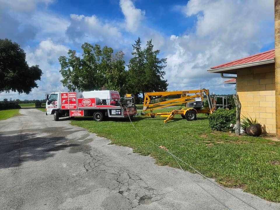 A red and white truck is parked on the side of the road next to a yellow crane.