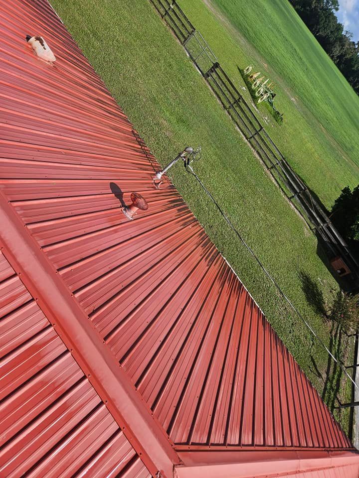 A red metal roof is sitting on top of a lush green field.