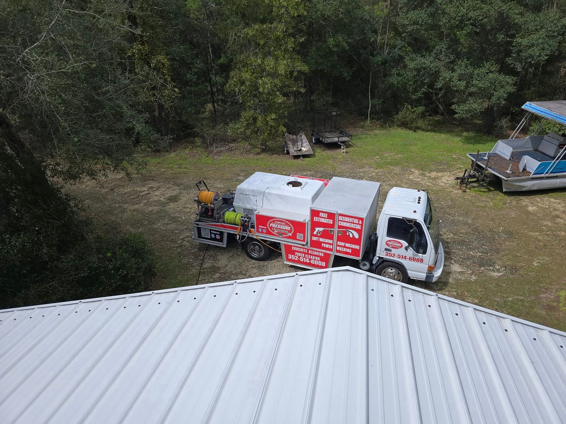 A white truck is parked on the roof of a building next to a boat.