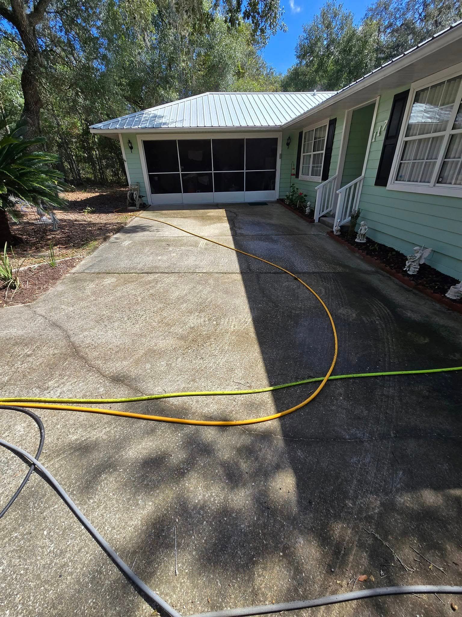 A hose is being used to clean the driveway of a house.